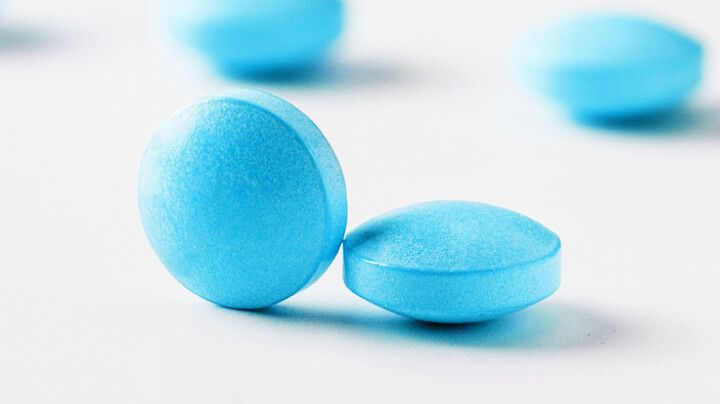 卫生保健和生物加工工业生产的亮蓝色药丸在白色表面上的极端特写