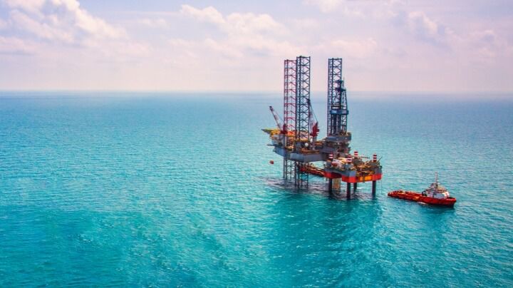 在明亮的蓝色海洋中，石油和天然气行业的海上钻井平台和红壳船