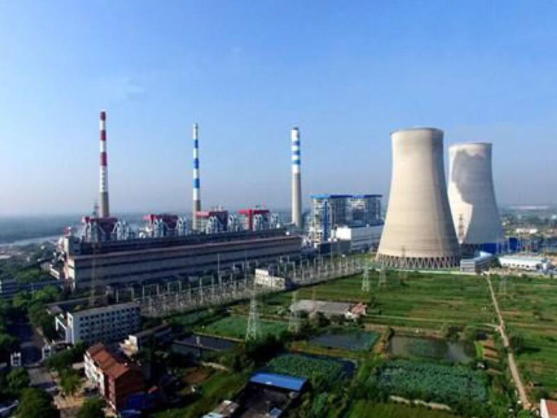 Aerial view of the Guodian Hanchuan power plant complex with two cooling towers, three striped smokestacks, grassy areas, buildings, pipes and roads