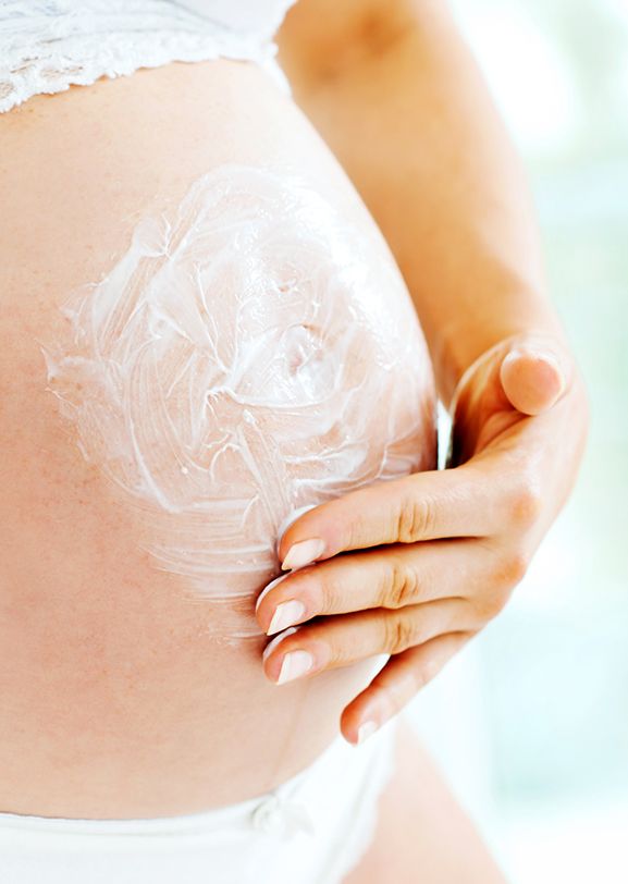 Schwangere Frau, die ein pharmazeutisches Produkt mit DuPont-Silikonlösungen für Narben und Dehnungsstreifen verwendet. 