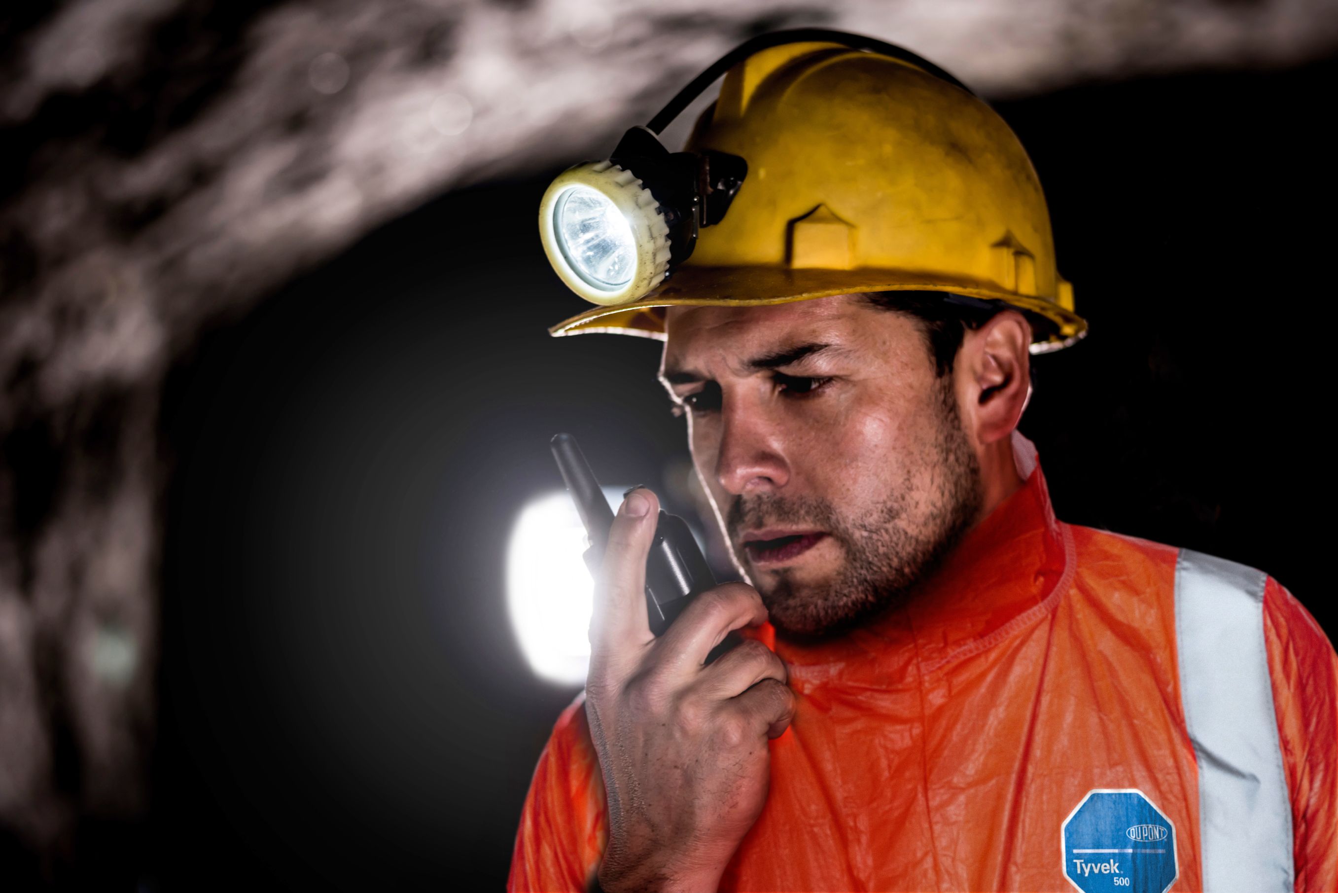 Portrait of a miner working at the mine and talking on a walkie-talkie 
