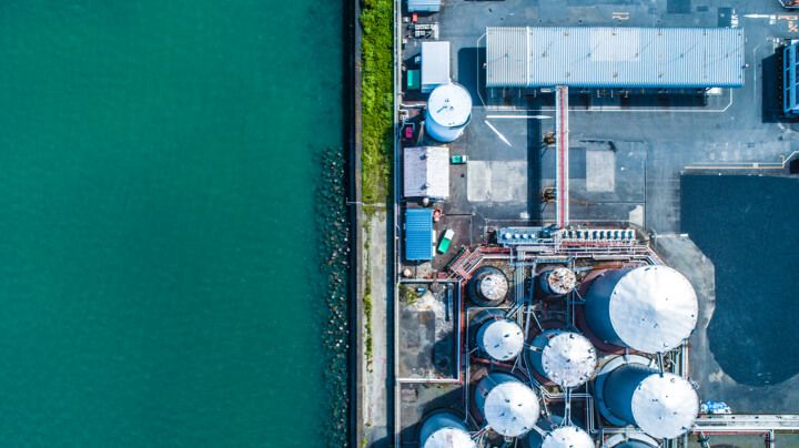 Aerial view of a chemical processing facility requiring industrial water treatment next to a flowing river.