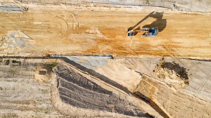 Aerial view of a large piece of excavation equipment on the dusty, scarred surface of a coal mine