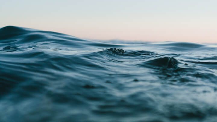 An extreme closeup of blue-green seawater reflecting the sky.