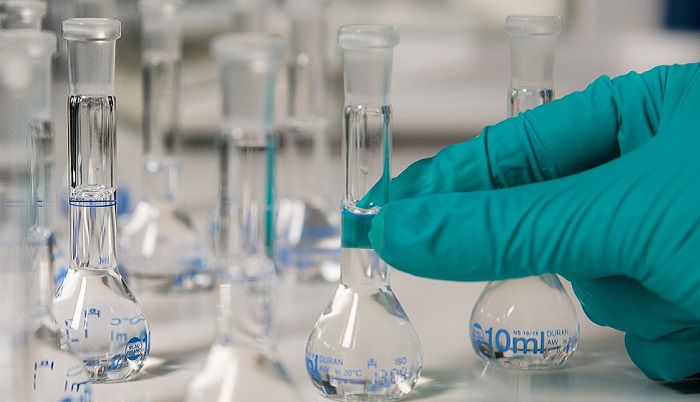 Person performing system optimization services testing beakers of water