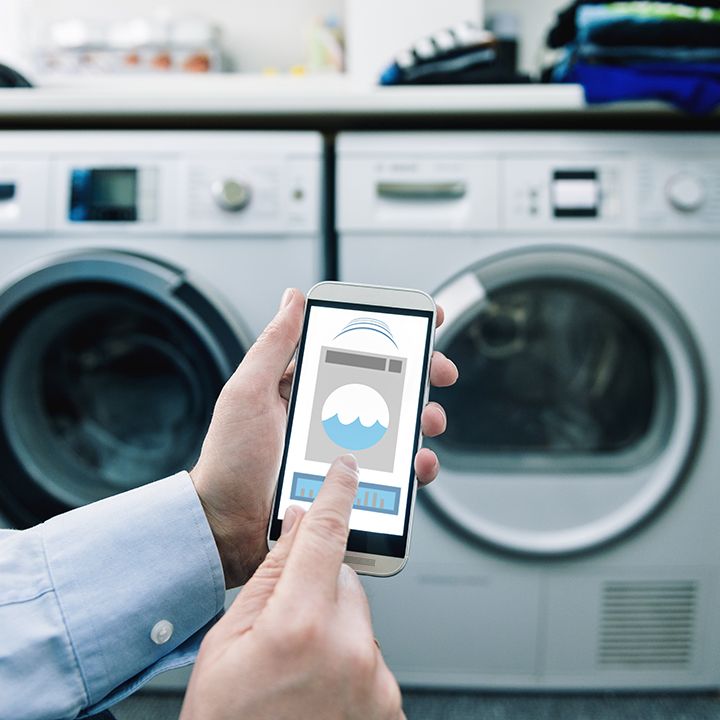 Man using smartphone to control washer and dryer.