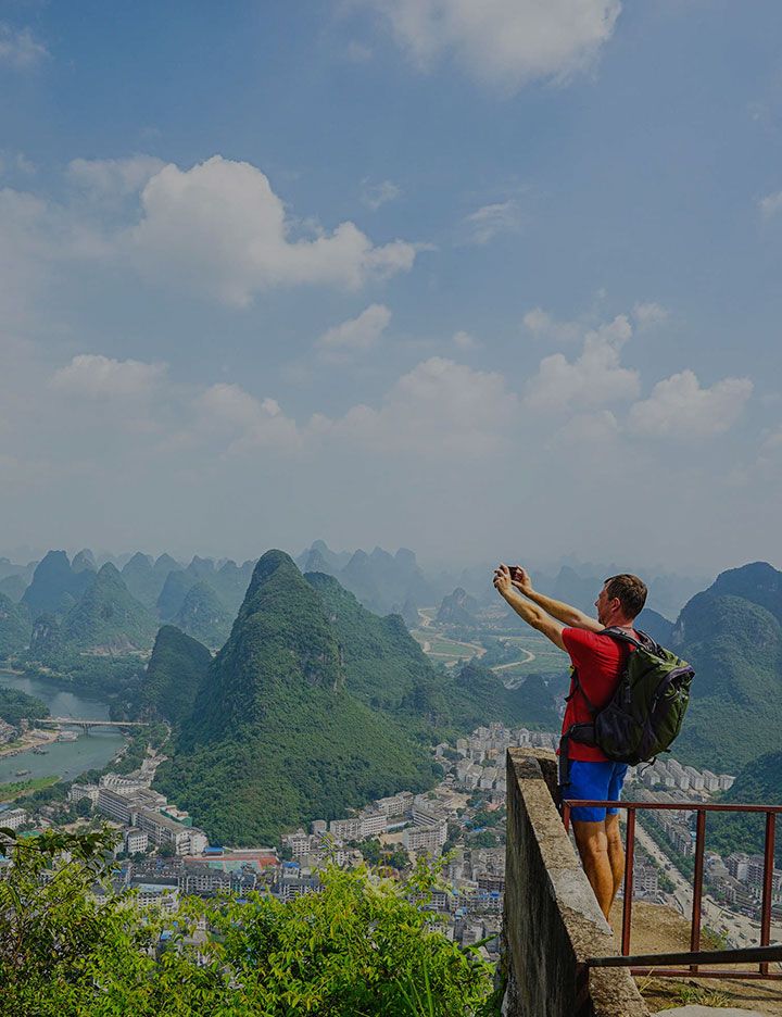 Man with backpack taking scenic picture with smartphone as an example of electrical technologies from DuPont