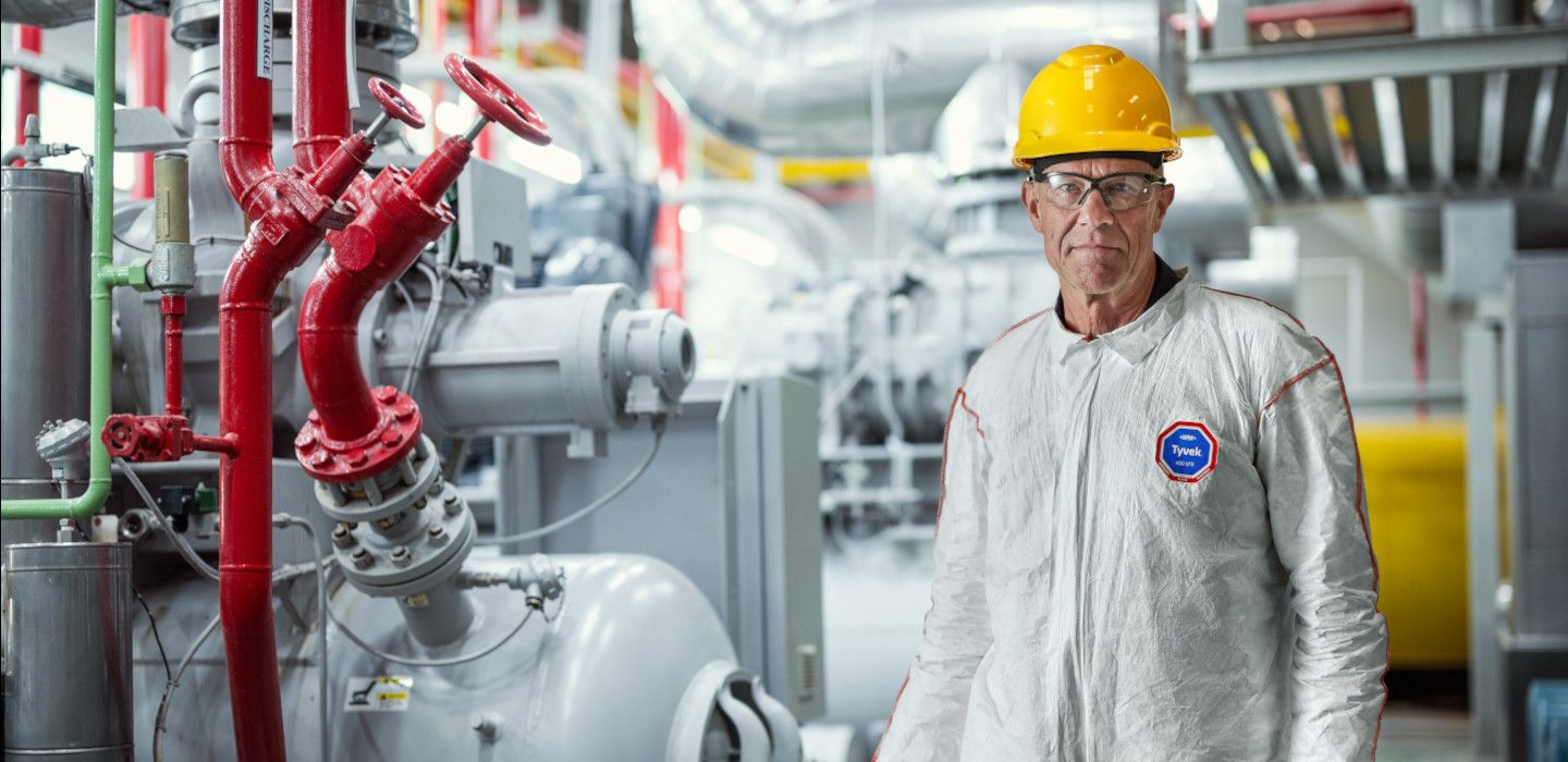 A portrait of CEO standing in a corridor of boiler control room and holding a digital tablet.